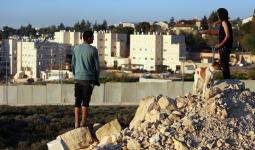 صورة توضيحية، فلسطينيون من مخيّم الجلزون للاجئين يطلّون من وراء الجدار على مستوطنة 
