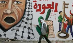 حاج فلسطيني يمشي أمام جدارية العودة في أحد المخيمات.jpg