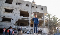 طفل يرفع علم فلسطين أمام منزله المدمر في العدوان الأخير على غزة