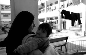 فلسطين،26 عاما، تحمل طفلها. هي أم تعيل وحدها سبعة أطفال. كانت حاملا في شهرها الثامن عندما تم تدمير منزلها وفرت حافية القدمين مع أسرتها الفتية إلى مركز الأونروا في تموز / يوليو 2015. الصورة: صورة الأمم المتحدة / الأونروا / شريف سرحان