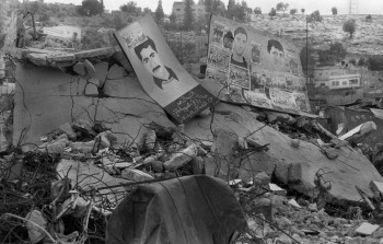 صورة لملصقات تحمل صورة شهداء وسط حطام مخيم جنين في الانتفاضة الثانية/ يونيو 2002
