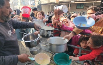 أطفال نازحون يحصلون على بعض الحساء من تكية خيرية في رفح