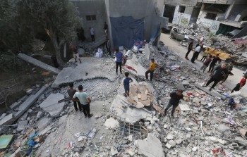 فلسطينيون يتفقدون الدمار في منزل قصفه الاحتلال بمخيم النصيرات وسط قطاع غزة