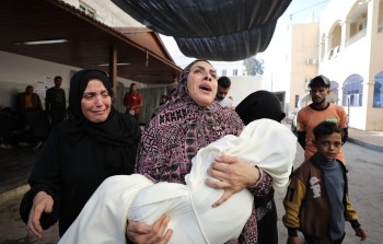 امرأة تحمل طفلها الشهيد في قطاع غزة  (GETTY)