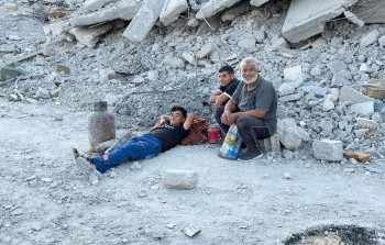 فلسطينيون عائدون إلى خان يونس يجلسون فوق ركام منازلهم