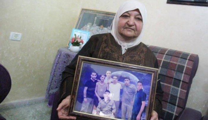 فلسطين المحتلة - أم ناصر أبو حميد تحمل صورة أبنائها الأسرى في سجون الاحتلال