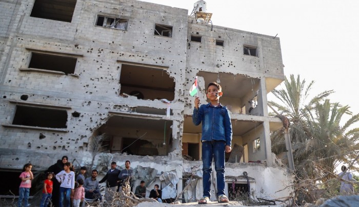 طفل يرفع علم فلسطين أمام منزله المدمر في العدوان الأخير على غزة